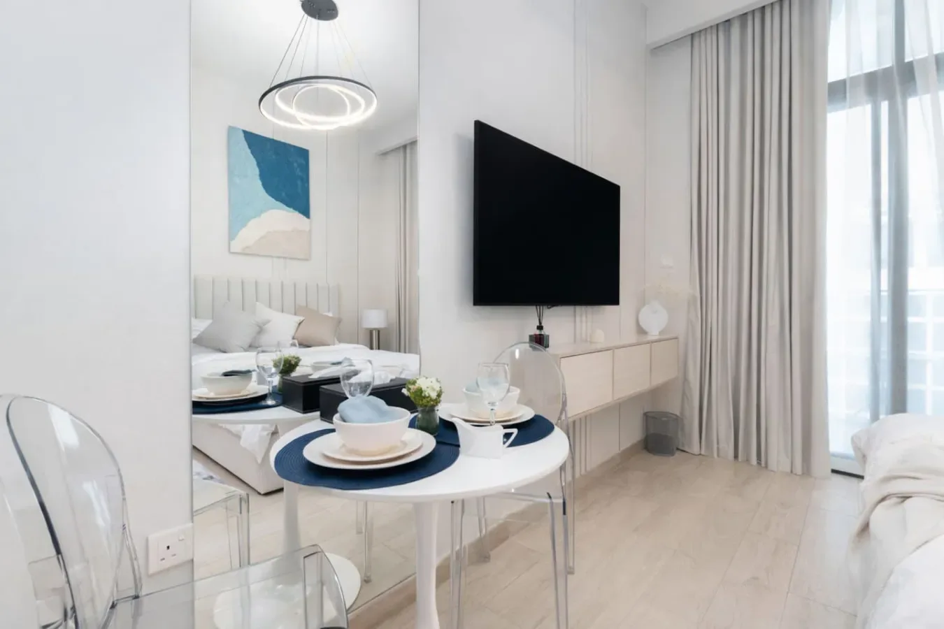 Un dormitorio luminoso con una mesa redonda puesta junto a la cama.