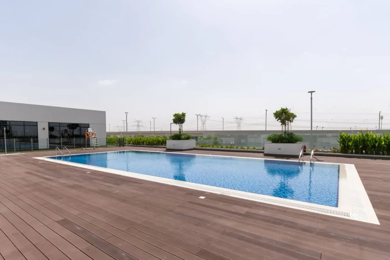 Una piscina al aire libre está junto a una amplia terraza de madera.