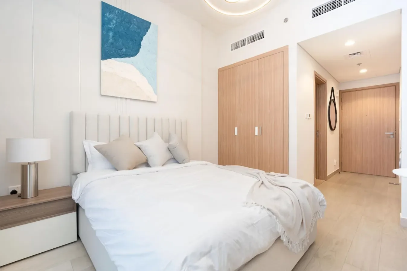 A bright bedroom with a bed and light wood cabinetry.