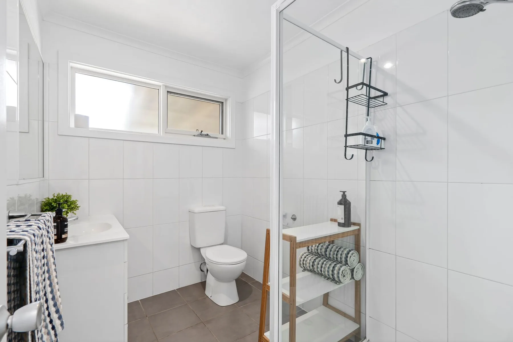 A bright bathroom with a vanity, toilet, and glass shower.
