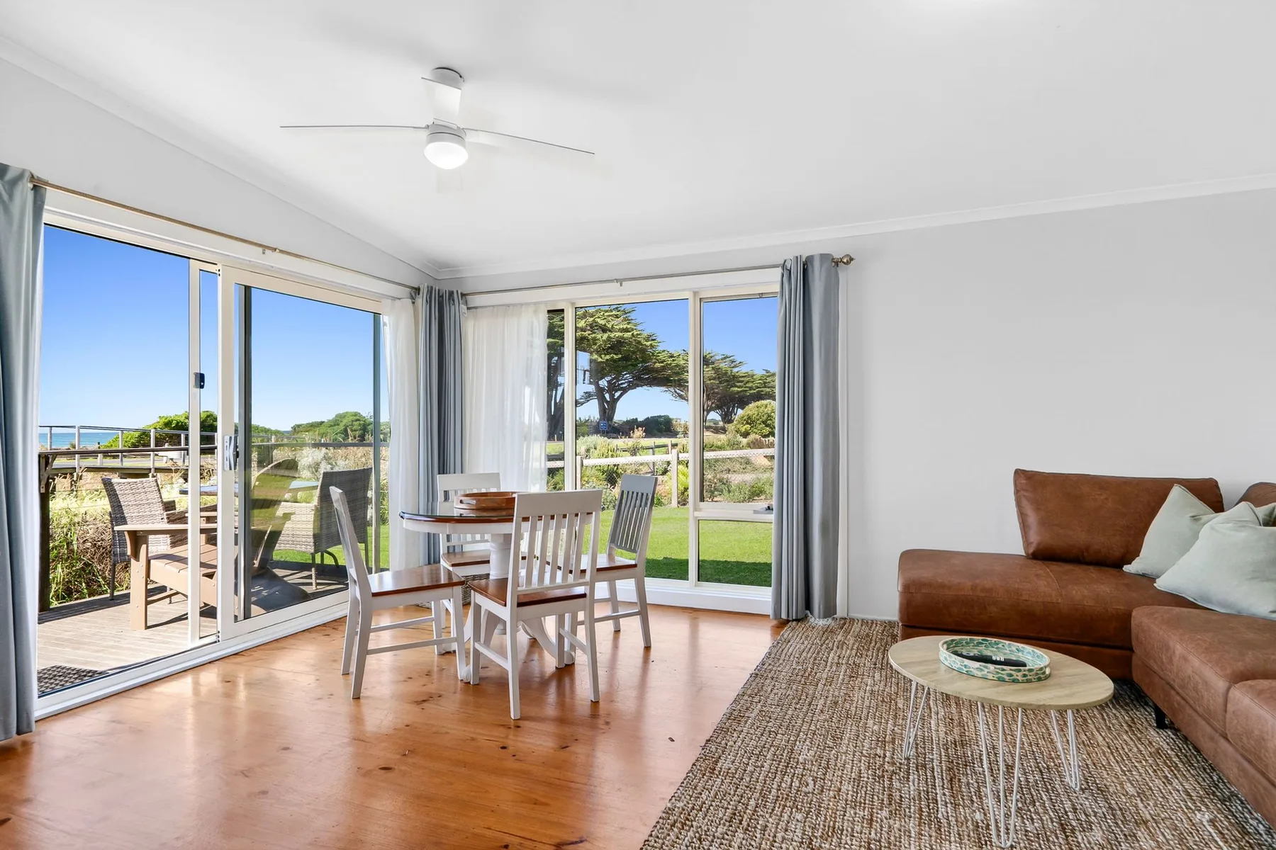 A bright living and dining area opens onto a patio through wide glass doors.