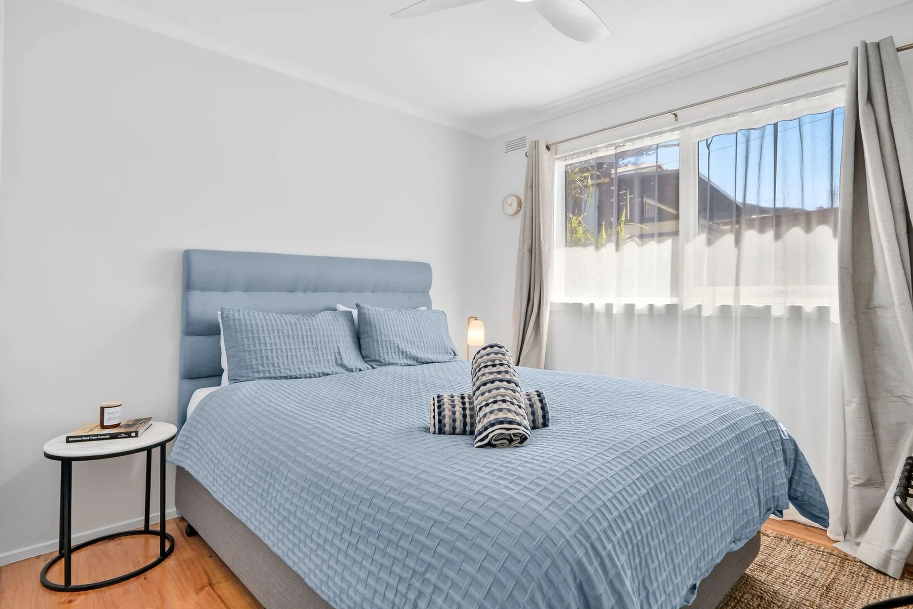 A bedroom with blue bedding beside a bright window.