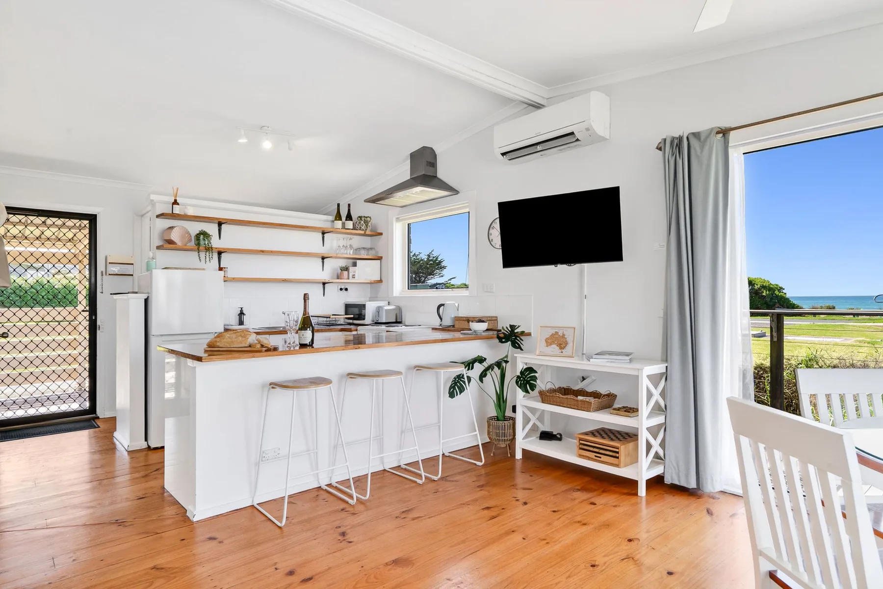 An open-plan kitchen and dining area with a breakfast counter and ocean view.