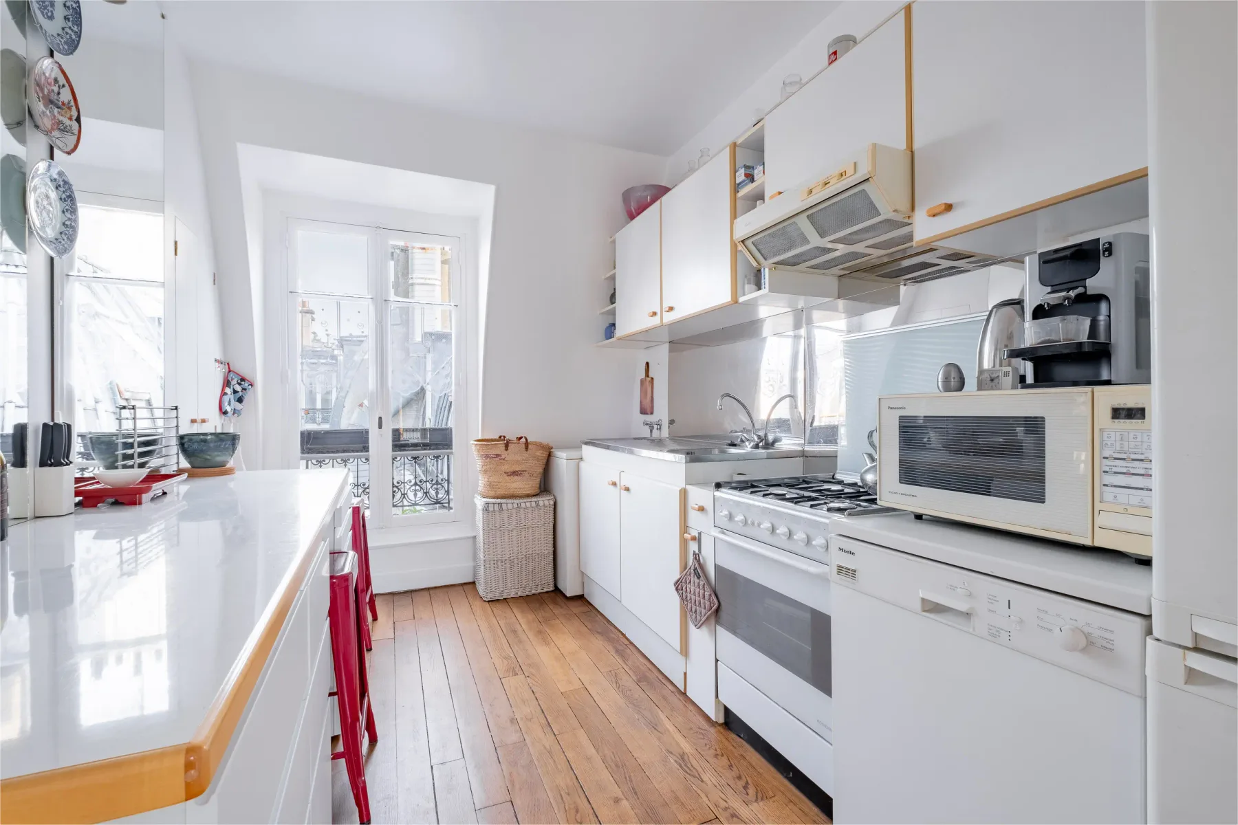 A bright kitchen with white cabinets, a stove, and a window.