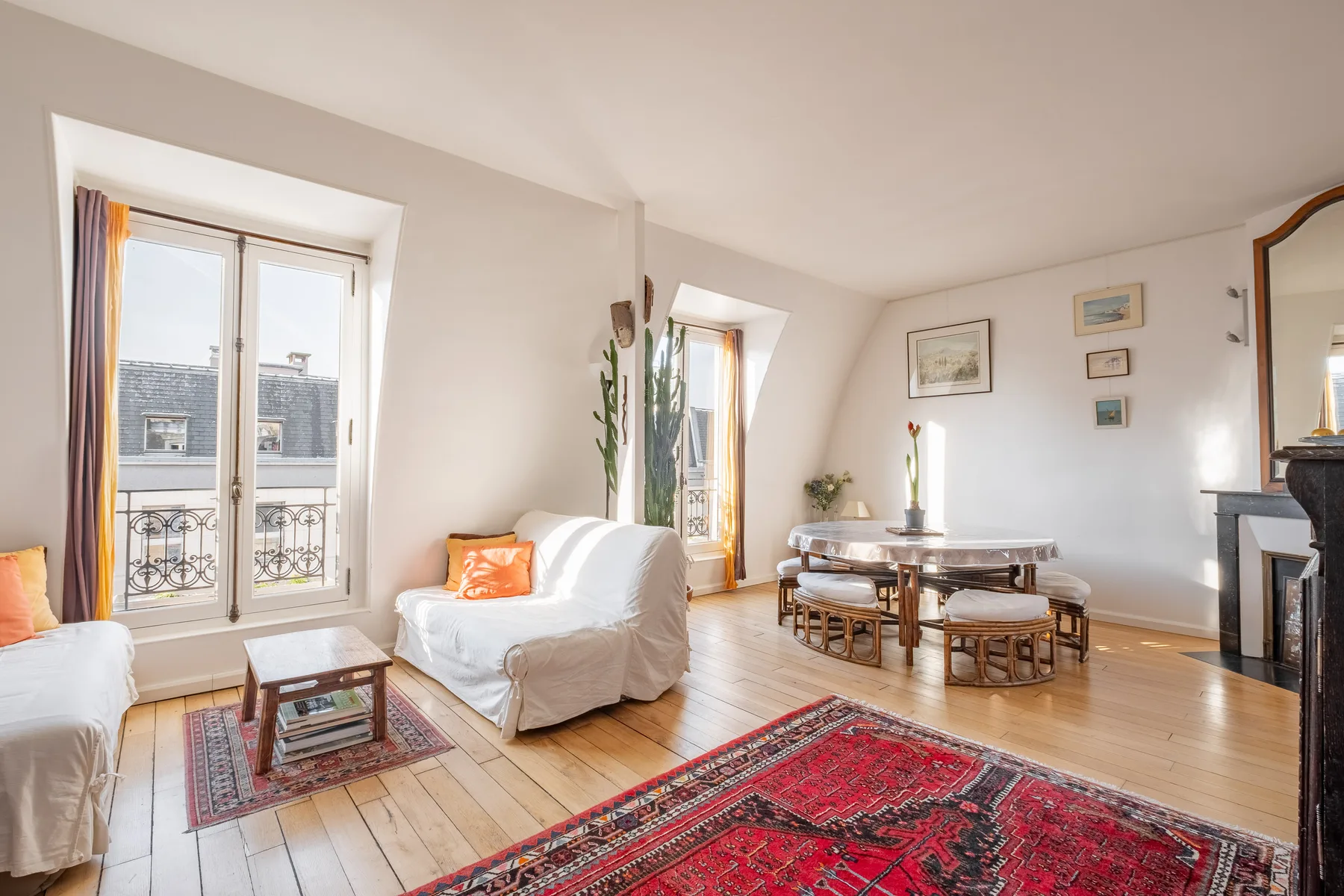 A bright living room with seating, a dining table, and a patterned rug.