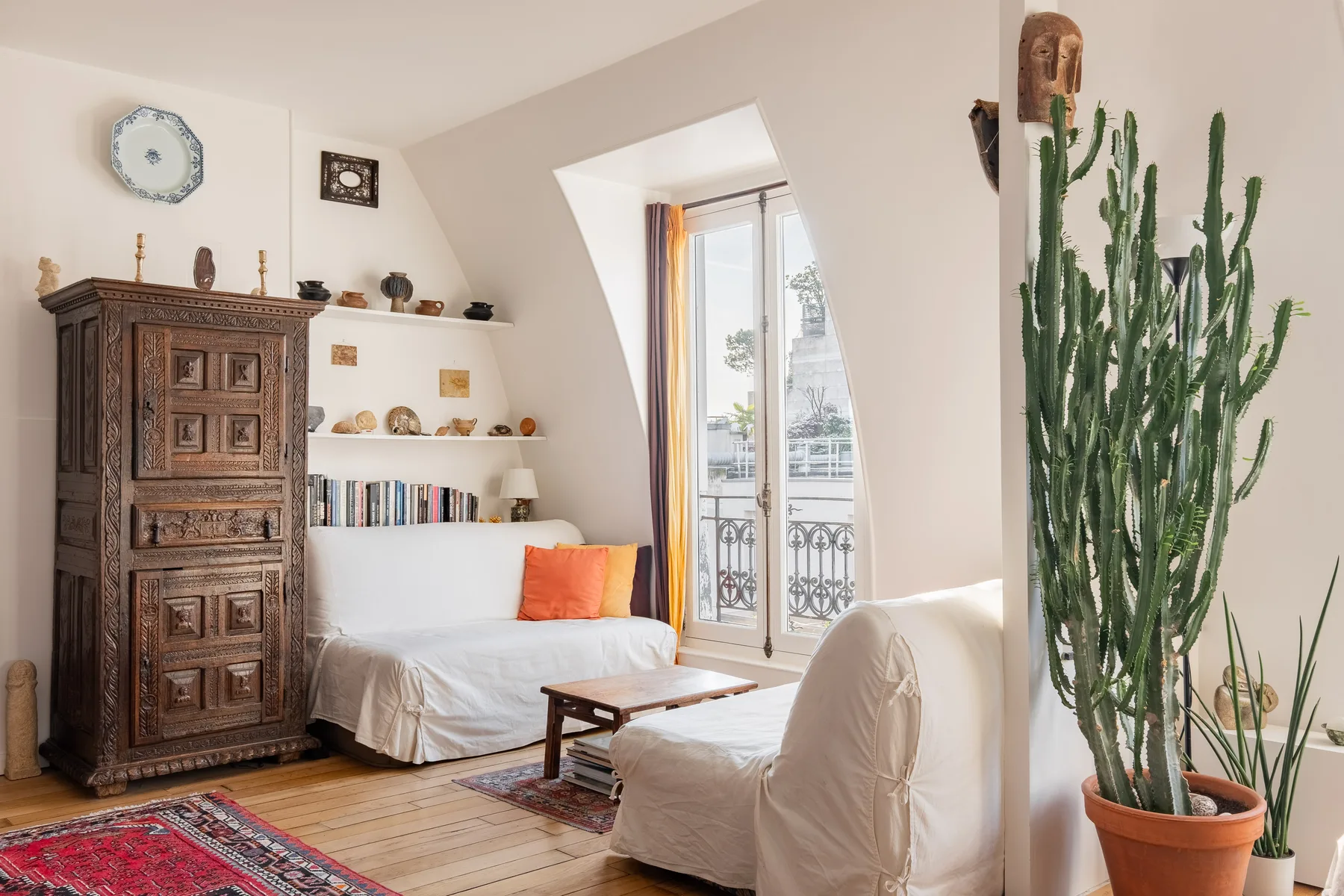 A bright living room with a white sofa and a tall potted cactus.