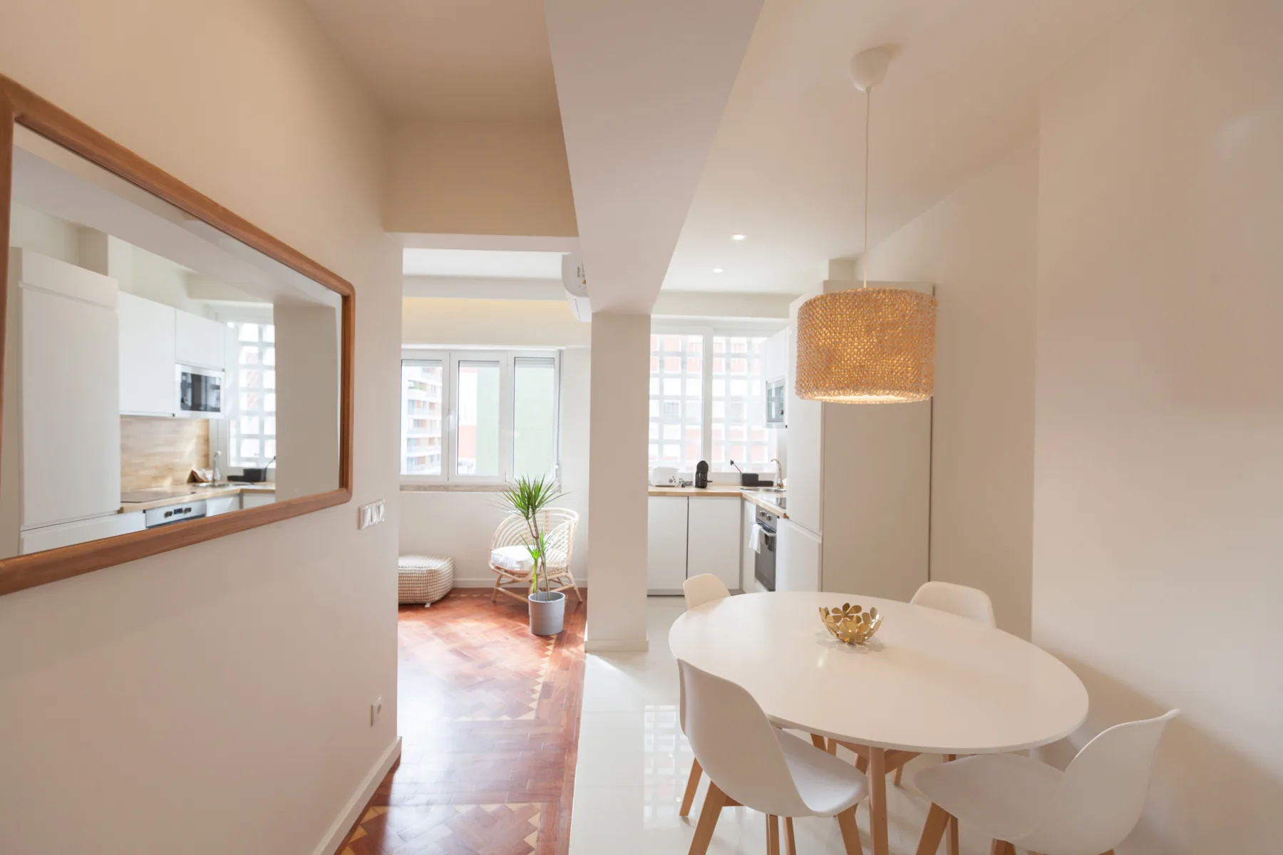 Un comedor luminoso con una mesa blanca y una cocina abierta al fondo.