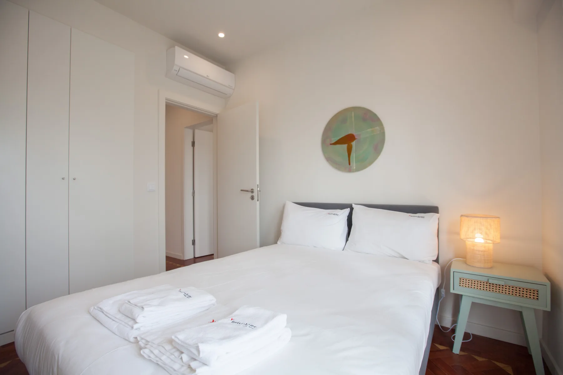 Un dormitorio con una cama bien hecha y una mesita de noche.