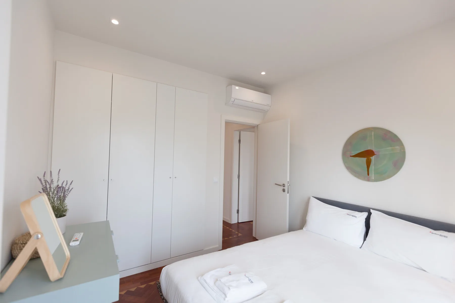 Un dormitorio luminoso con una cama, armarios empotrados y una puerta.