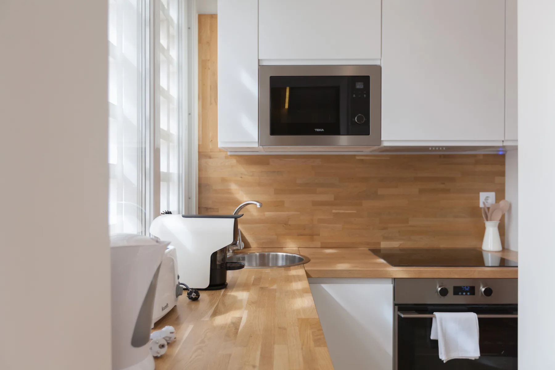 Una cocina luminosa con encimeras de madera y electrodomésticos integrados.