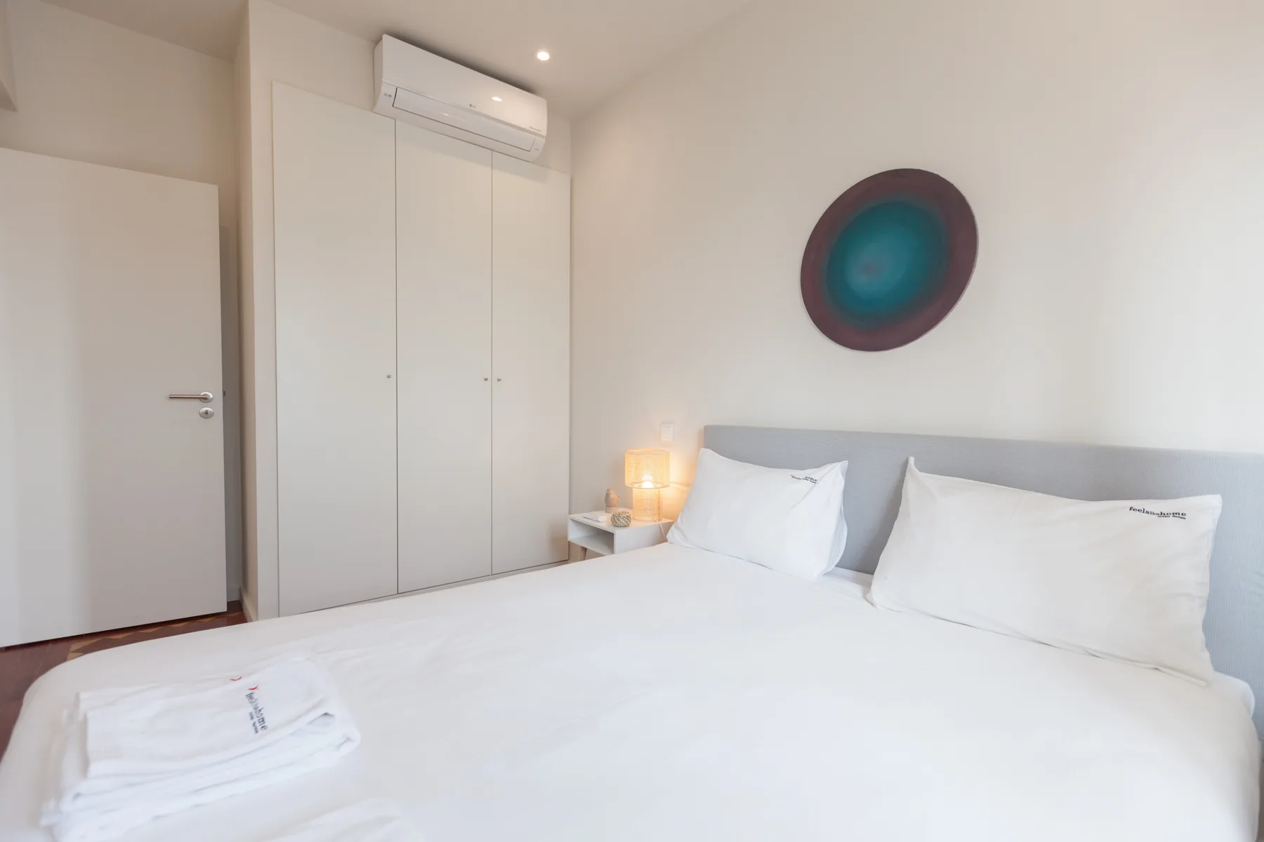 Un dormitorio con una cama bien hecha y arte circular en la pared.