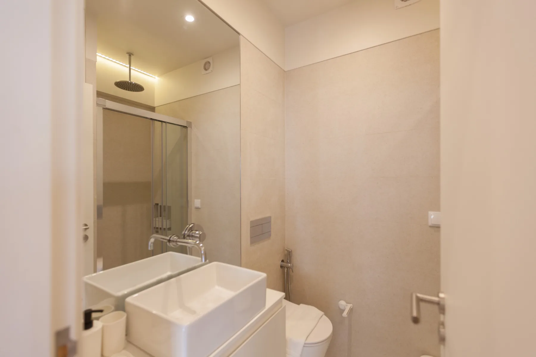 Un baño con azulejos, ducha de vidrio, lavabo e inodoro.