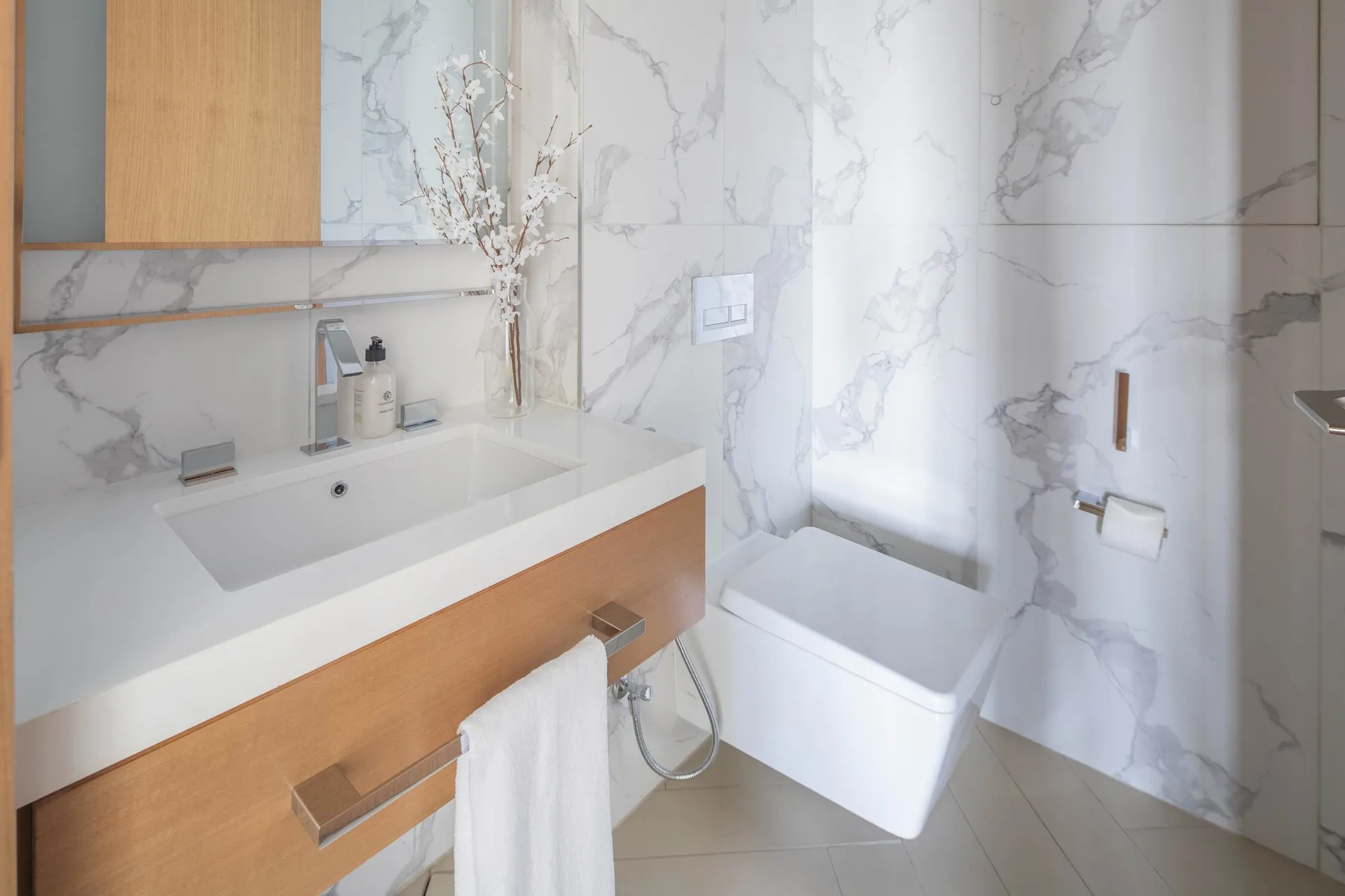 A bathroom with a sink and bathtub against marble-patterned walls.