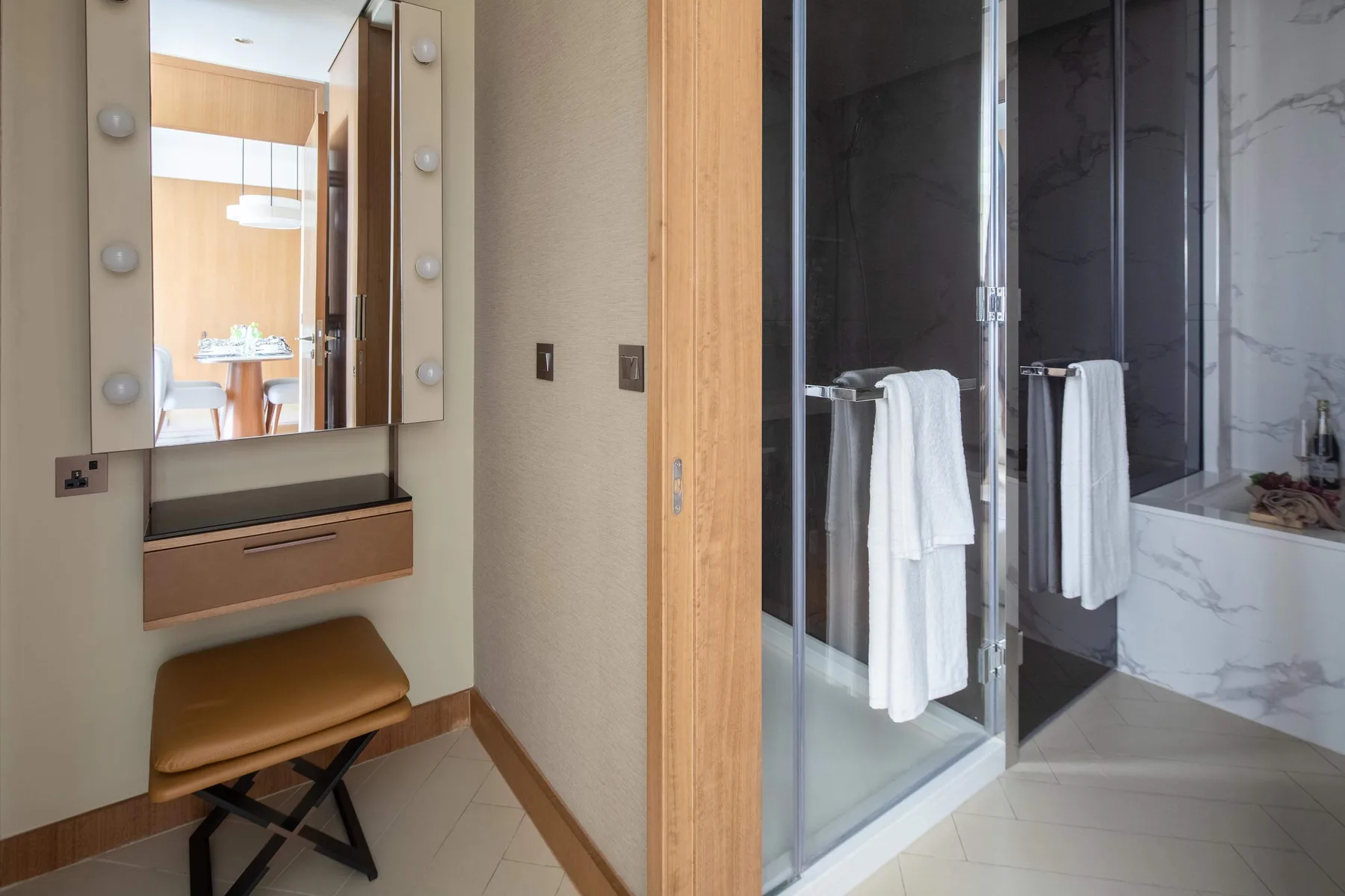 A bathroom vanity and a glass shower with towels are visible.