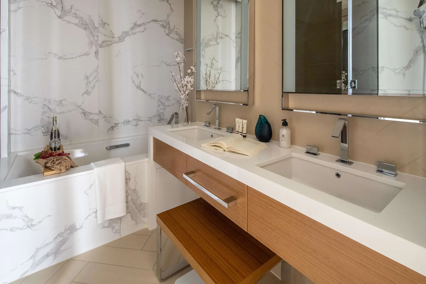 A bright bathroom with a bathtub and a long vanity with two sinks.