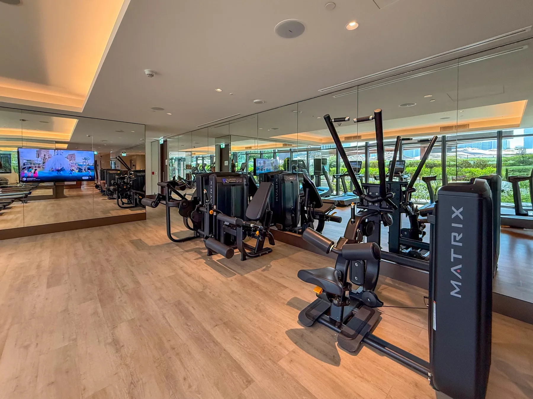 A fitness room with exercise machines and mirrored walls.