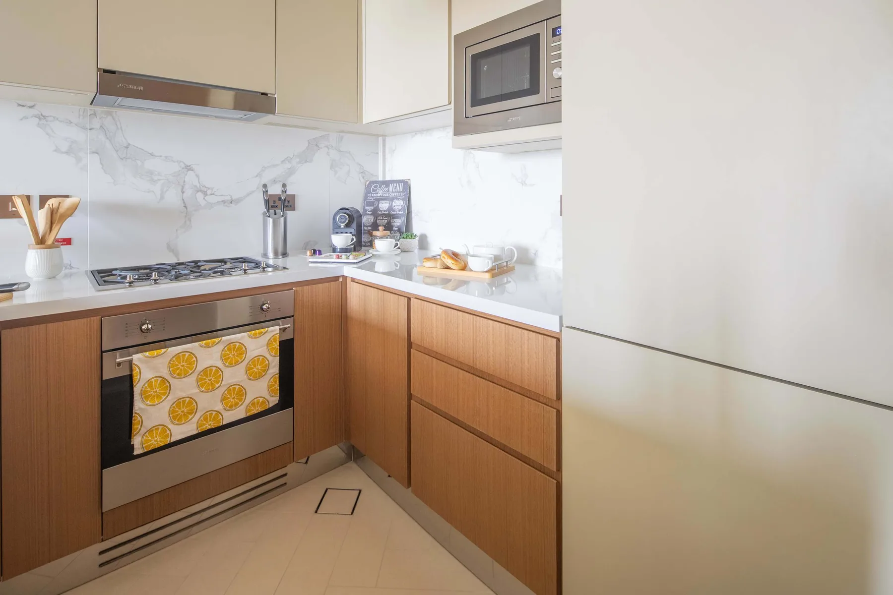 A modern kitchen with wood cabinetry, a cooktop, and a countertop microwave.