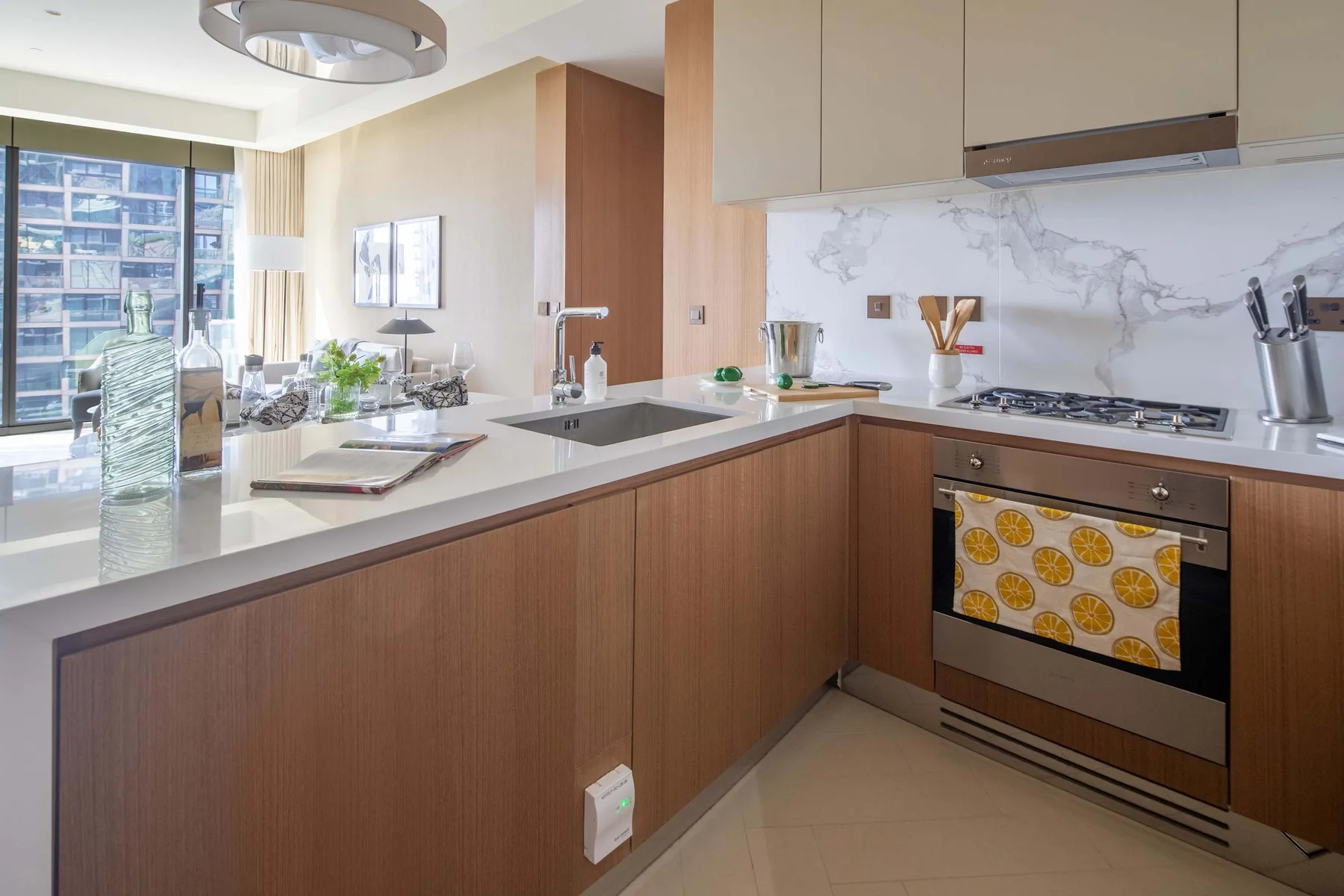 A modern kitchen with an island, built-in oven, and large windows.