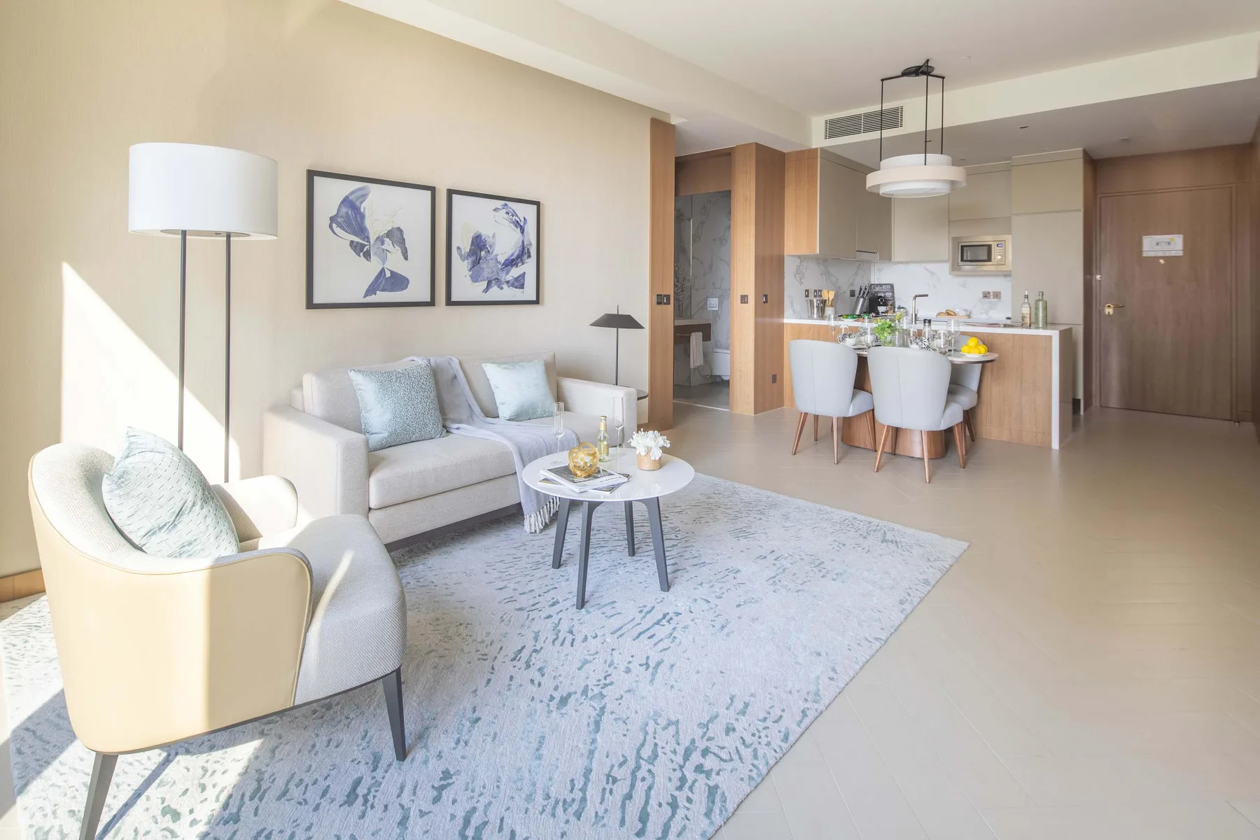 A bright living area with seating, a coffee table, and an adjoining kitchen.