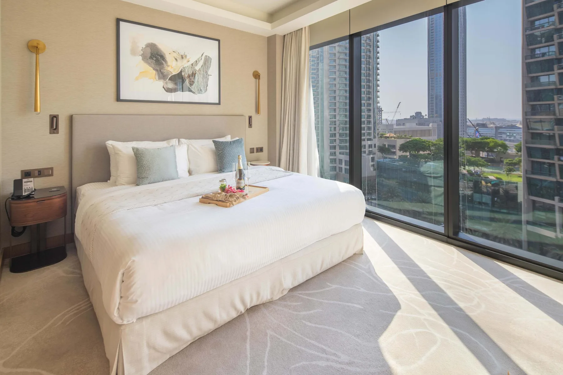 A bright bedroom features a neatly made bed beside large windows.