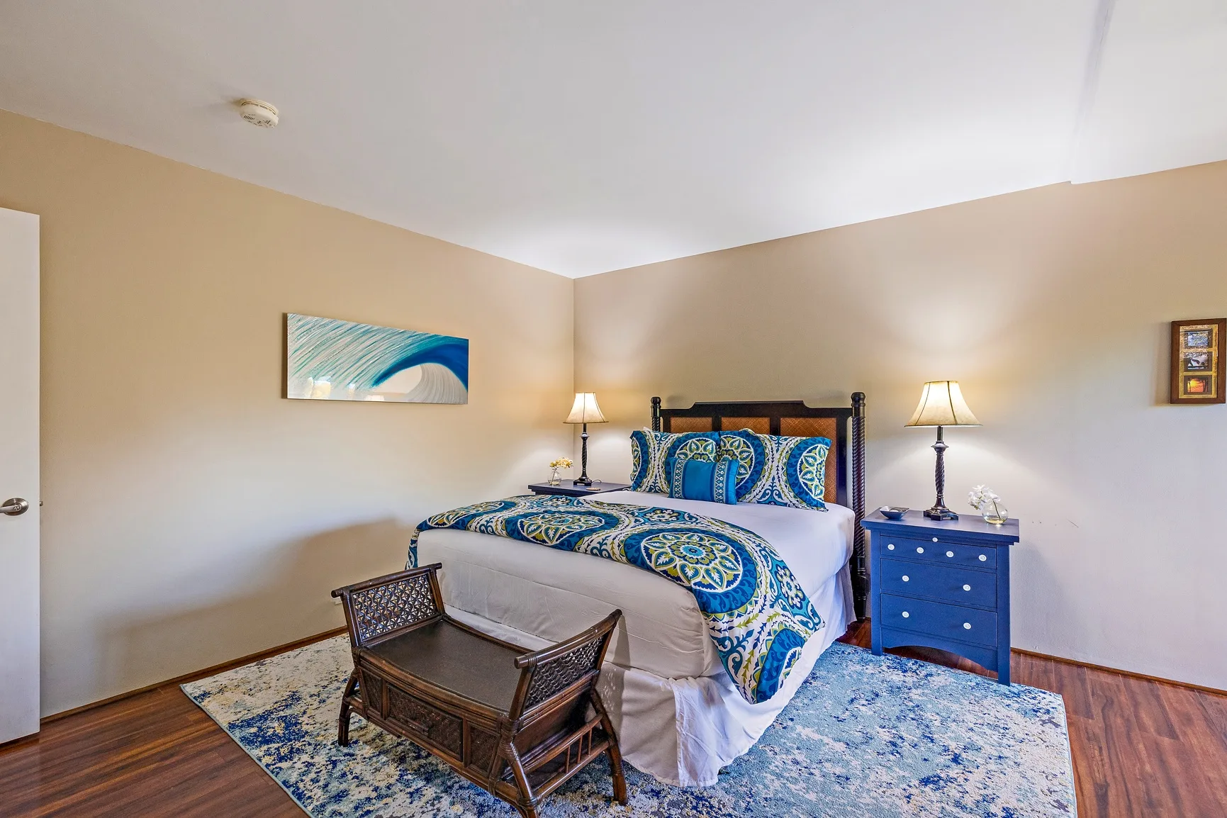 Un dormitorio con una cama, ropa de cama azul y lámparas a los lados.