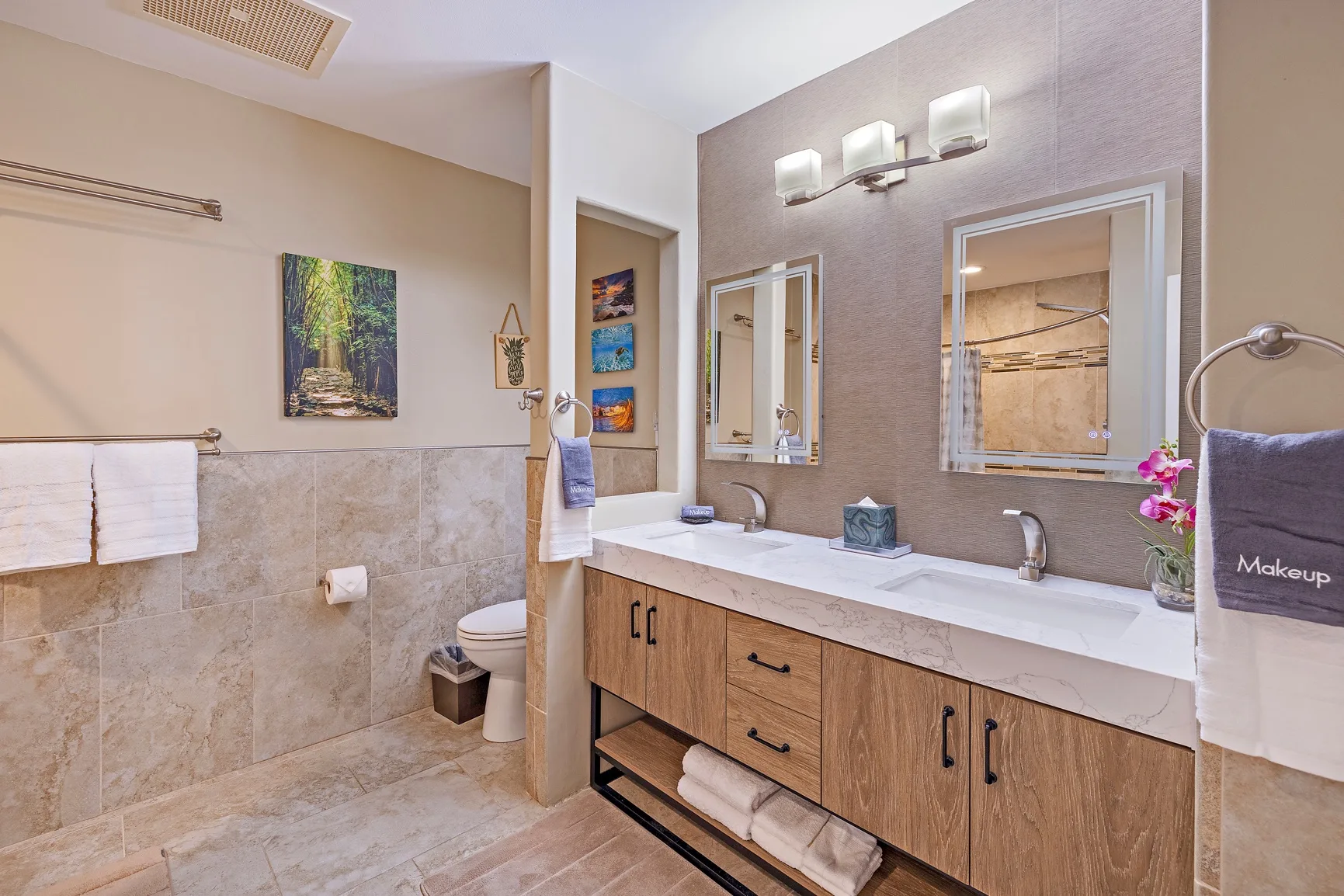 Un baño con un mueble largo, dos lavabos y un inodoro.