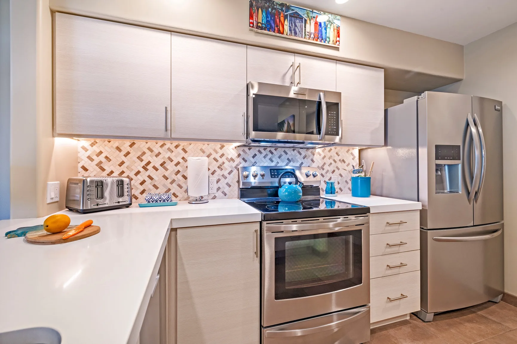 Una cocina moderna con gabinetes claros, electrodomésticos de acero inoxidable y azulejos decorativos.