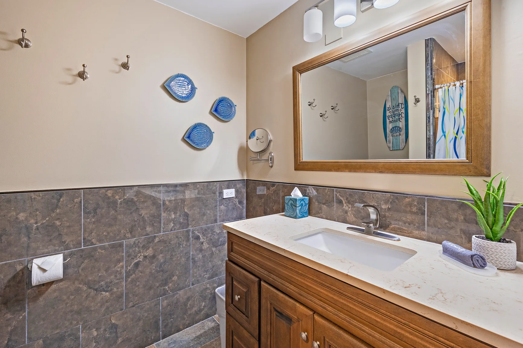 Un tocador de baño con lavabo, espejo grande y ganchos en la pared.