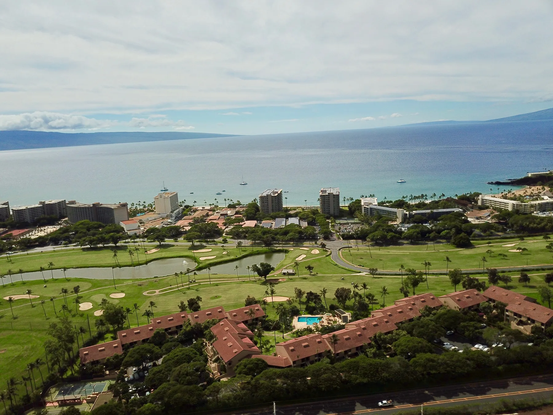 Un paisaje costero contempla una bahía, con zonas verdes y edificios en primer plano.