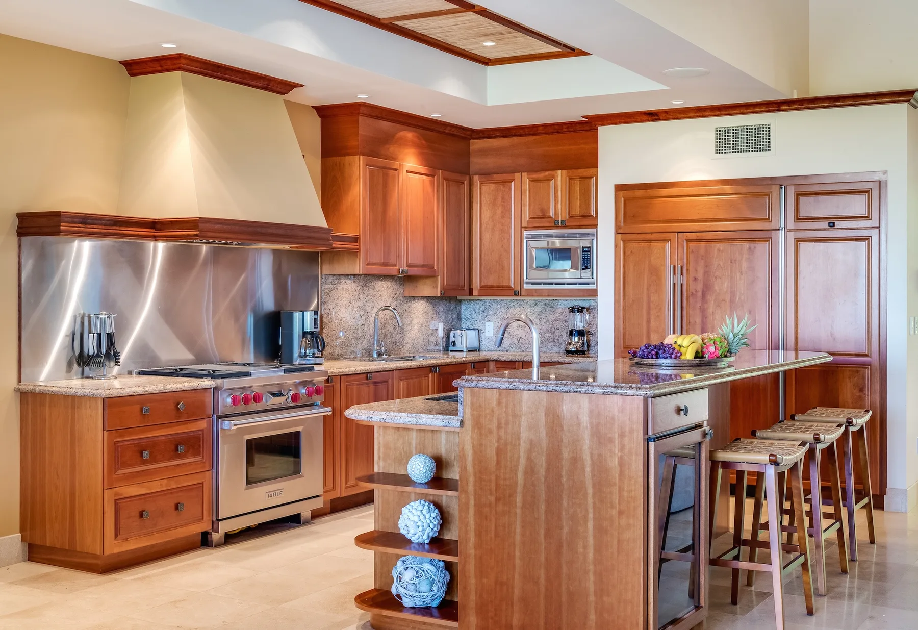 Una cocina amplia con gabinetes de madera, electrodomésticos de acero inoxidable e isla central.