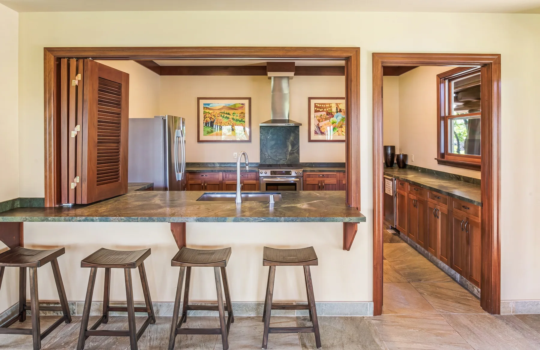 Una cocina con una barra y taburetes se abre a un comedor.