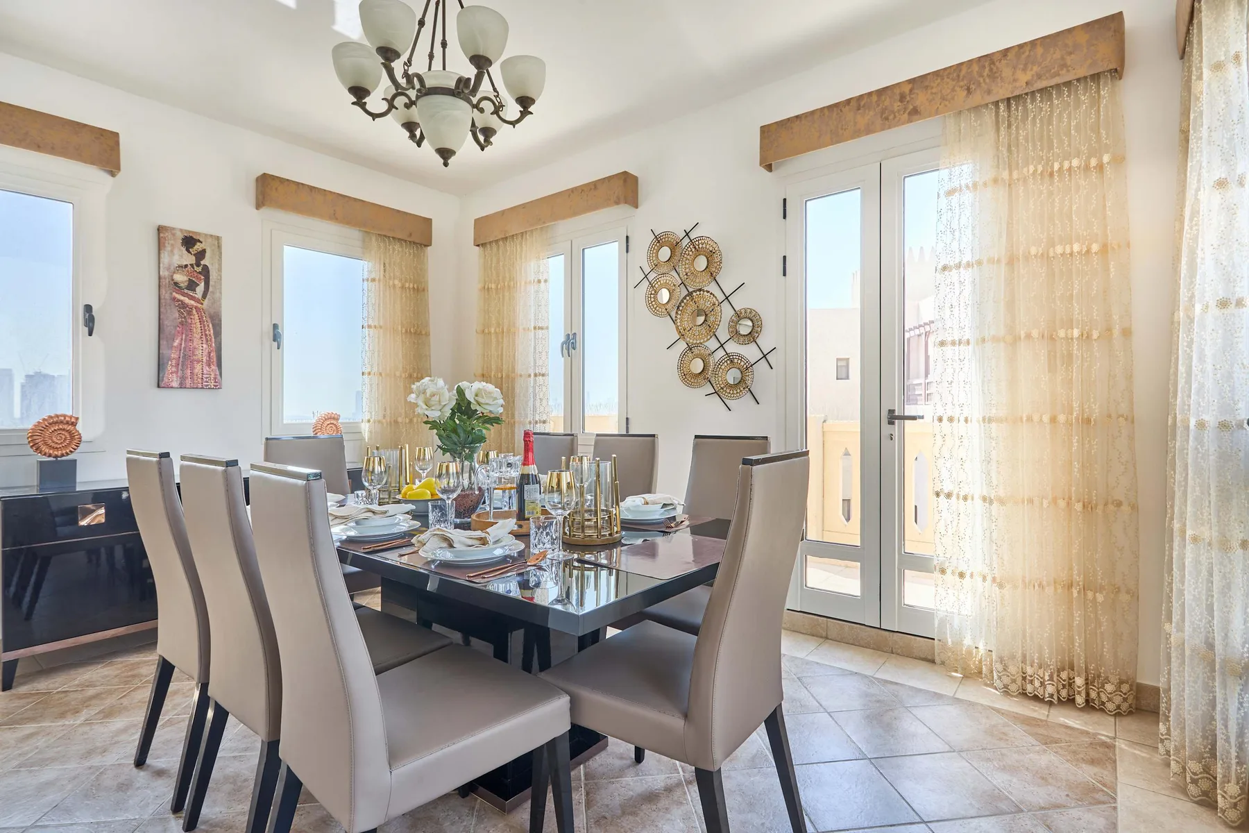 Un comedor con una mesa puesta junto a grandes ventanas y puertas de vidrio.