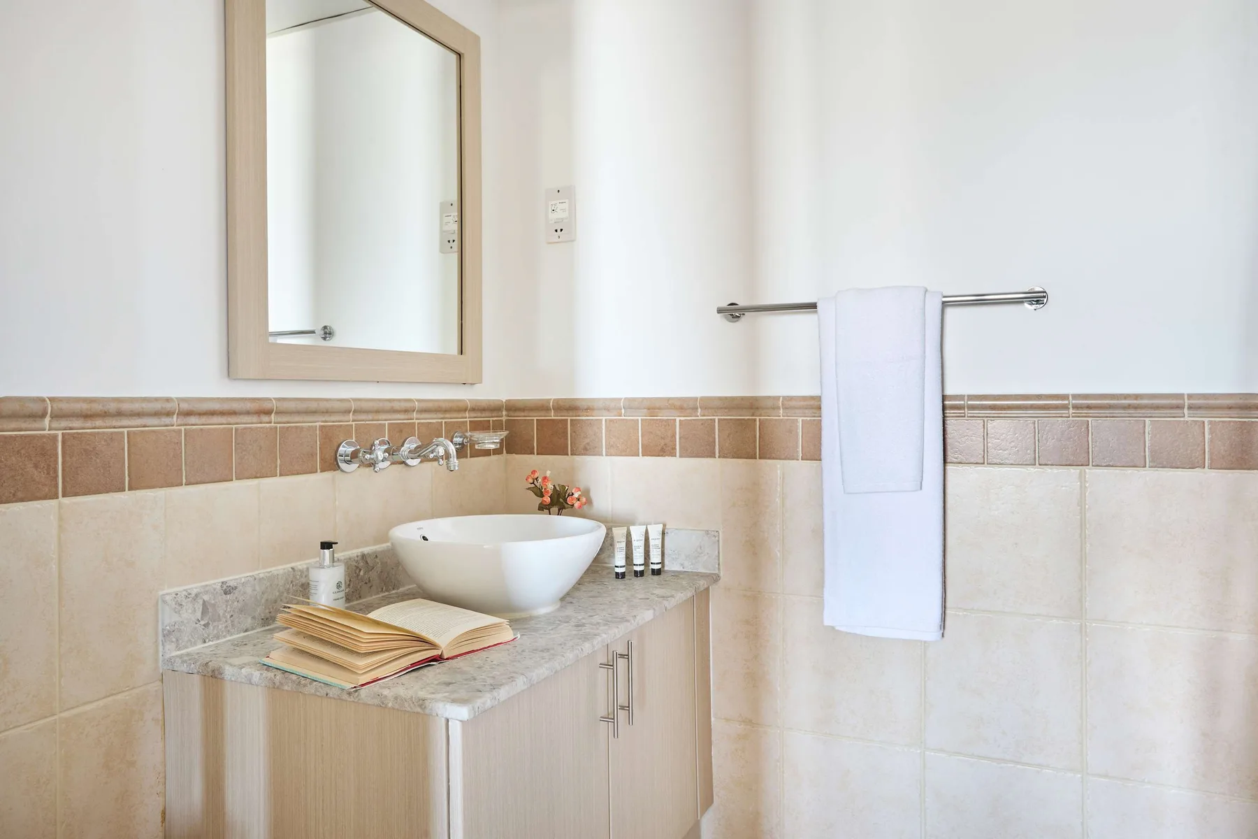 Un baño luminoso con tocador, lavabo, espejo y toallero.