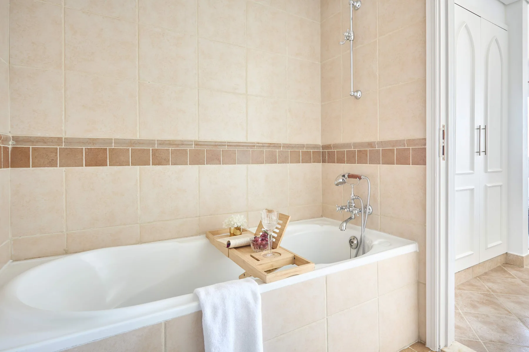 Un baño alicatado con bañera y grifería de ducha.