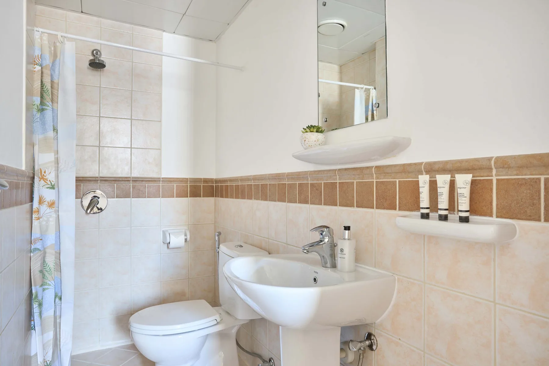 Un baño con azulejos, lavabo, inodoro y cortina de ducha.