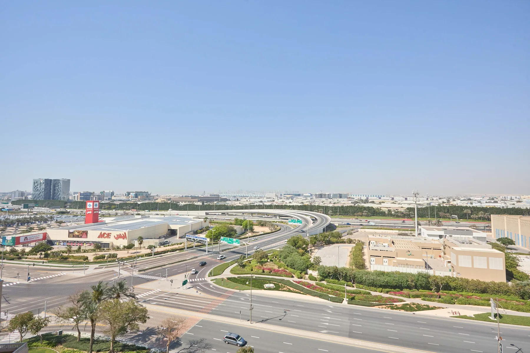 Un amplio enlace de autopistas atraviesa una zona urbanizada bajo un cielo despejado.