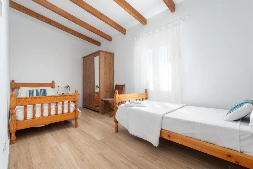 A bright bedroom with wooden beds and a wardrobe.