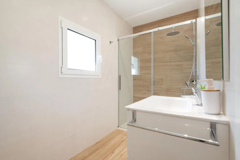 A bright bathroom with a vanity and glass-enclosed shower.