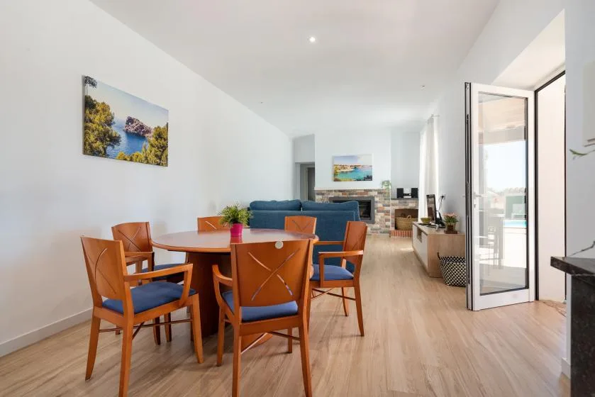 A bright living and dining area with a wooden table and blue seating.