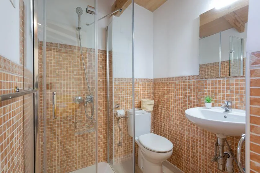 A tiled bathroom with a glass shower, toilet, and sink.