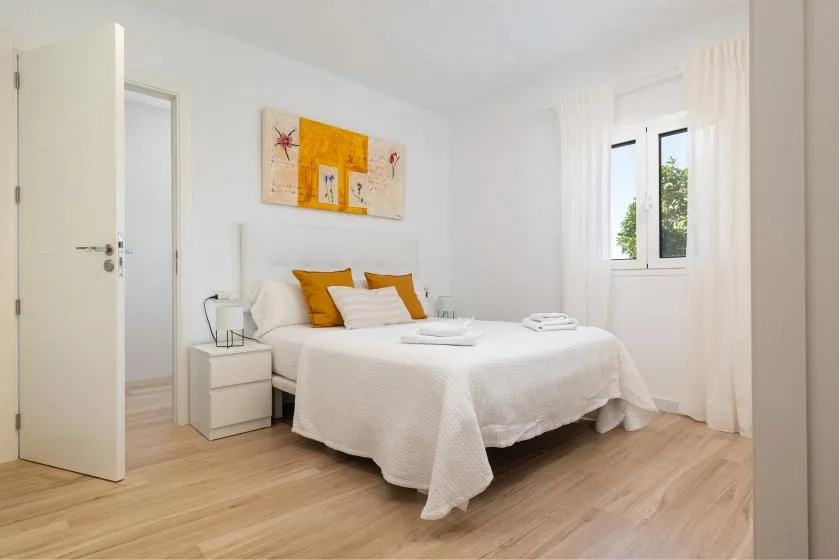 A bright bedroom with a neatly made bed and a window.