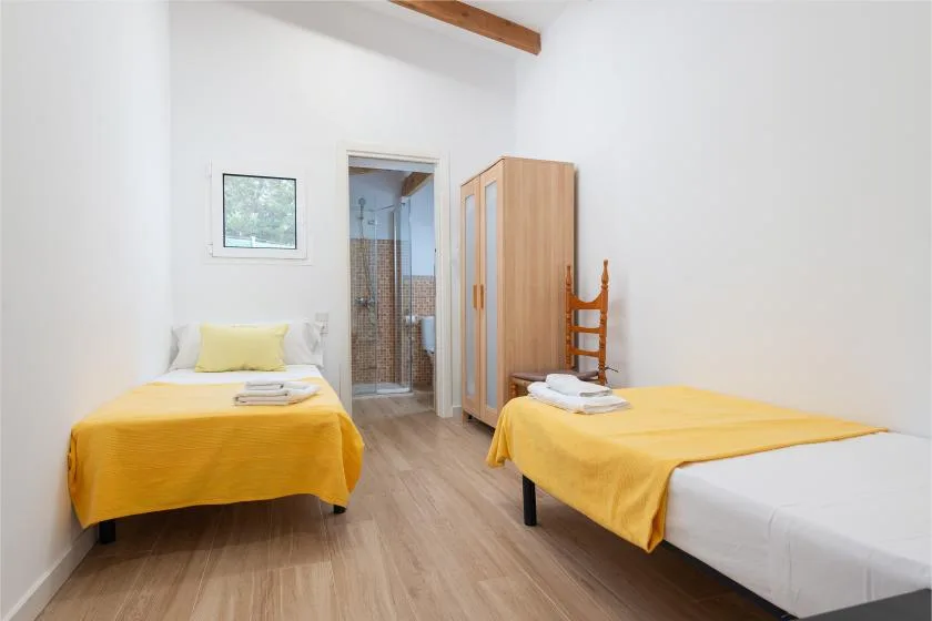 A bedroom with two beds covered in yellow bedding and a wardrobe.