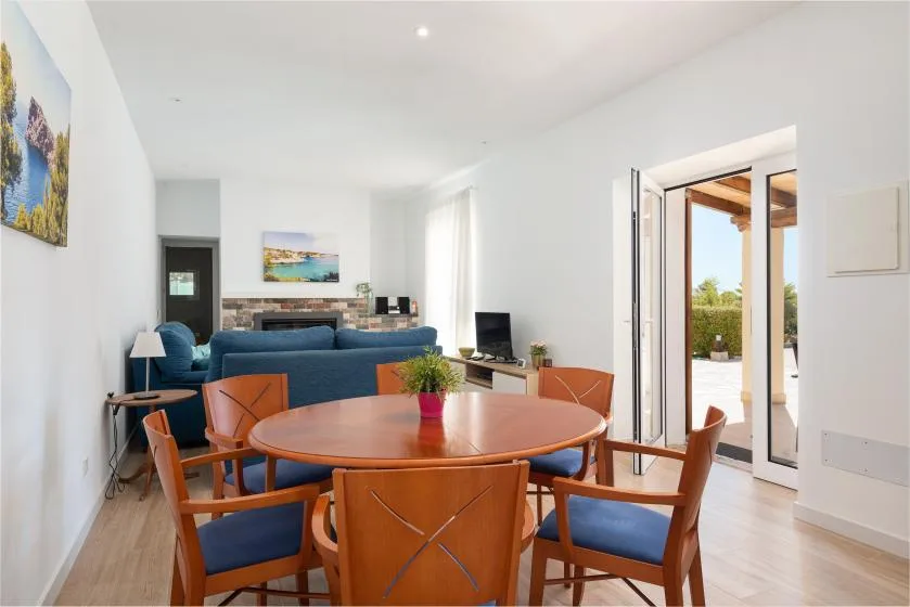 A bright living and dining area with a round table and blue seating.