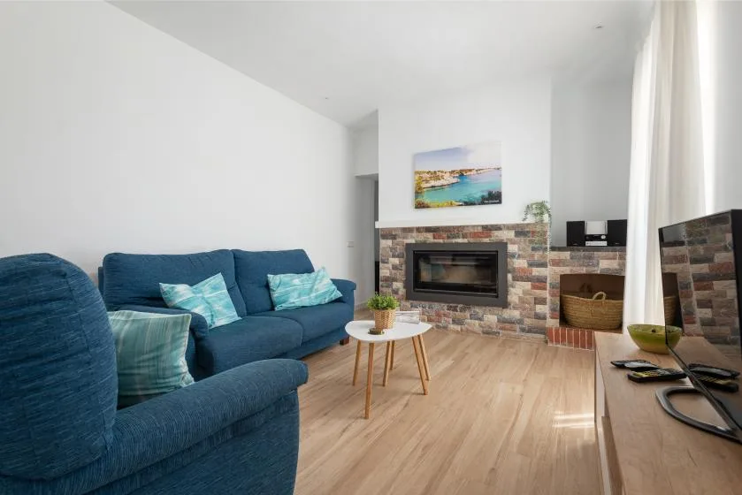 A living room with blue seating, a fireplace, and a television.