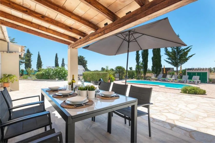 A covered outdoor dining area overlooks a swimming pool and landscaped grounds.