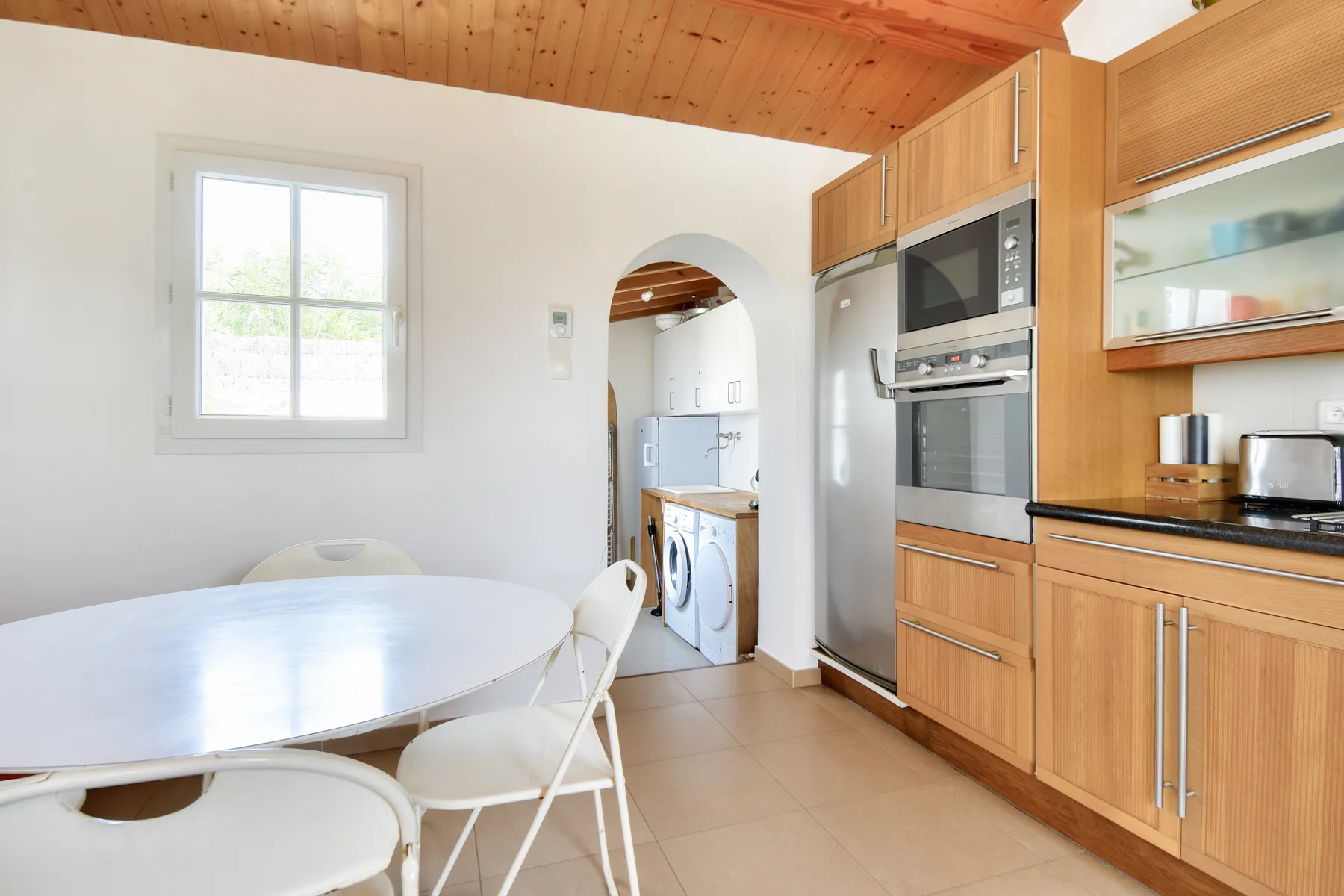 A bright kitchen and dining area with wooden cabinetry and a round table.