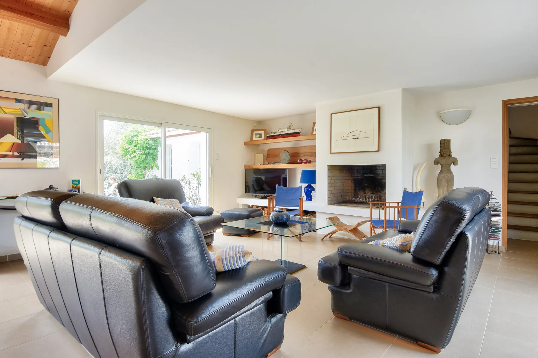 A living room with black leather seating and a fireplace.