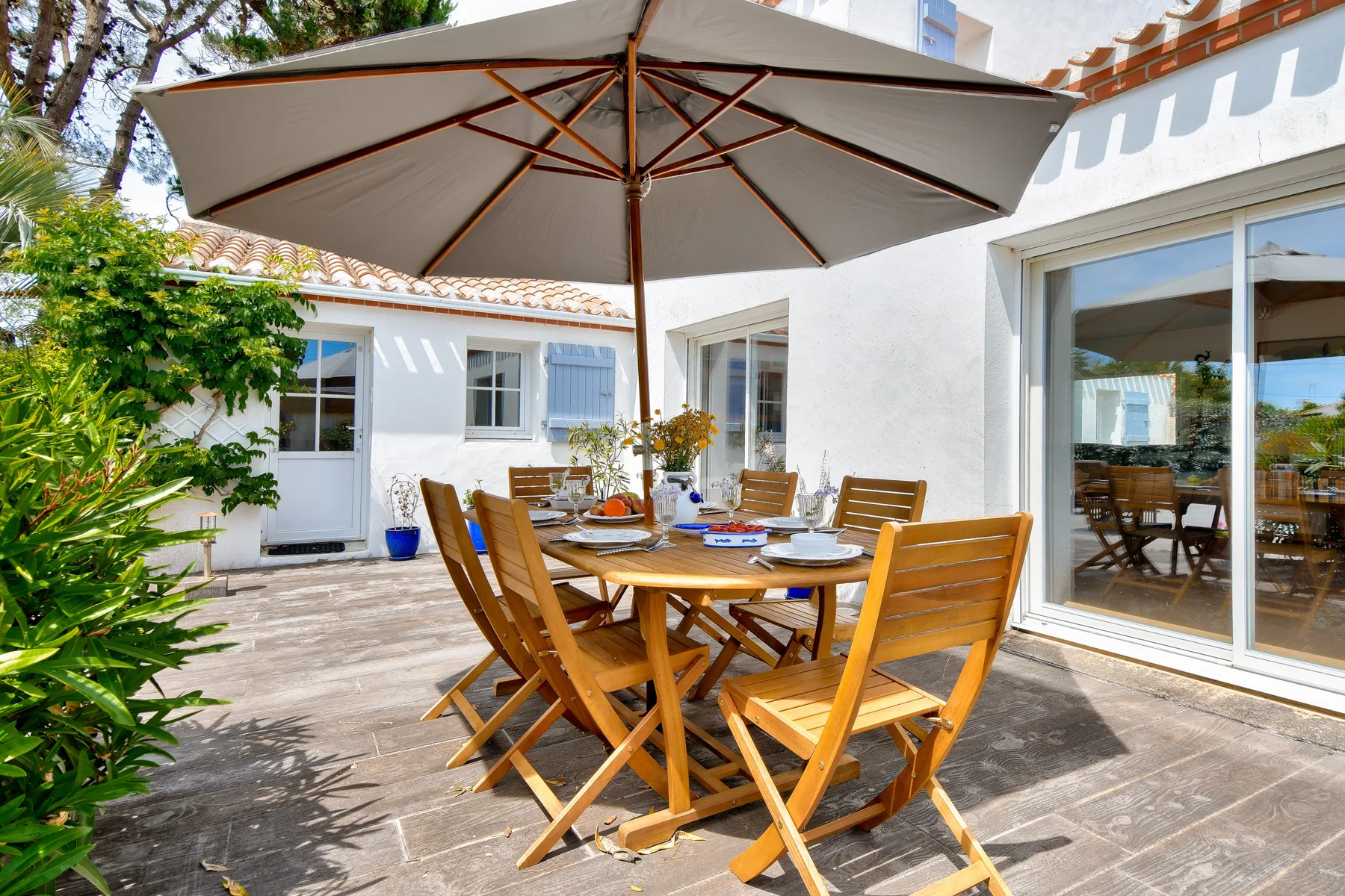 Outdoor dining area with a wooden table and chairs beneath a large umbrella.