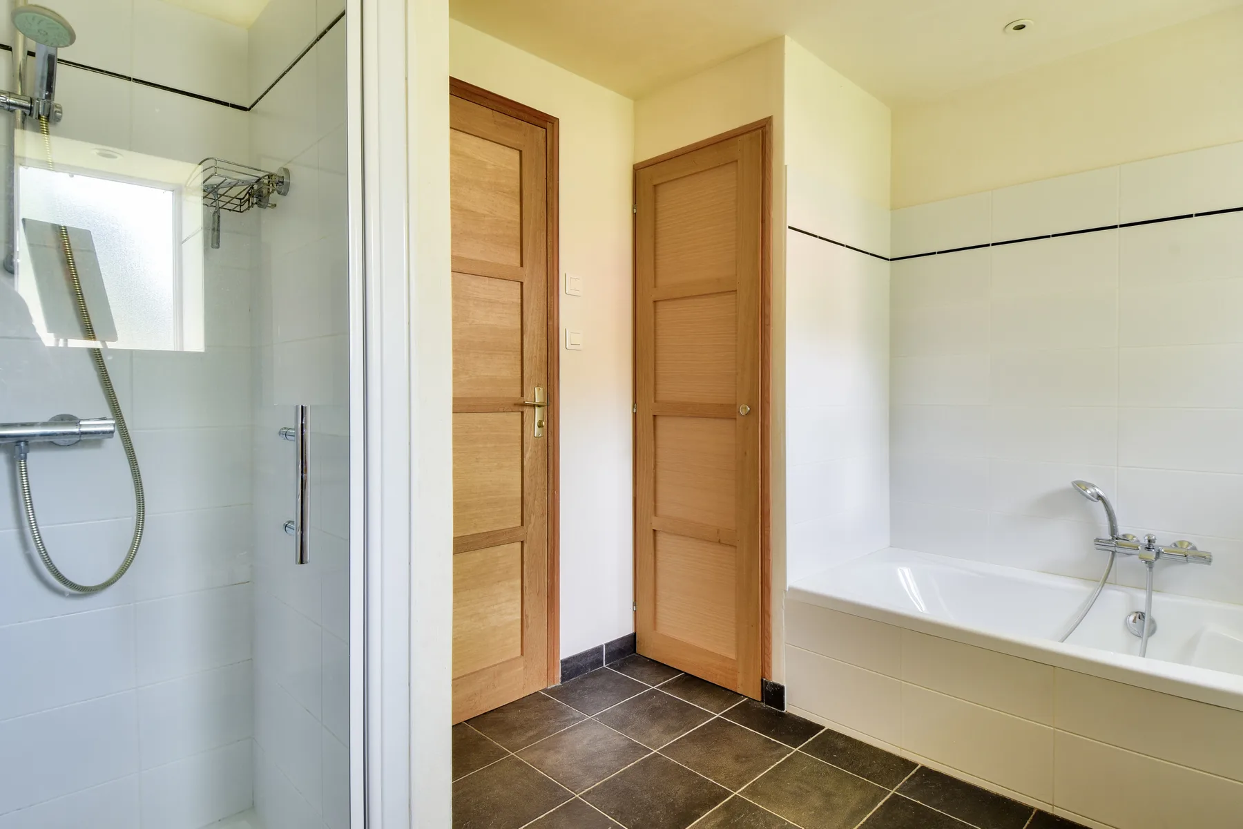 A bathroom with a shower, bathtub, and two wooden doors.