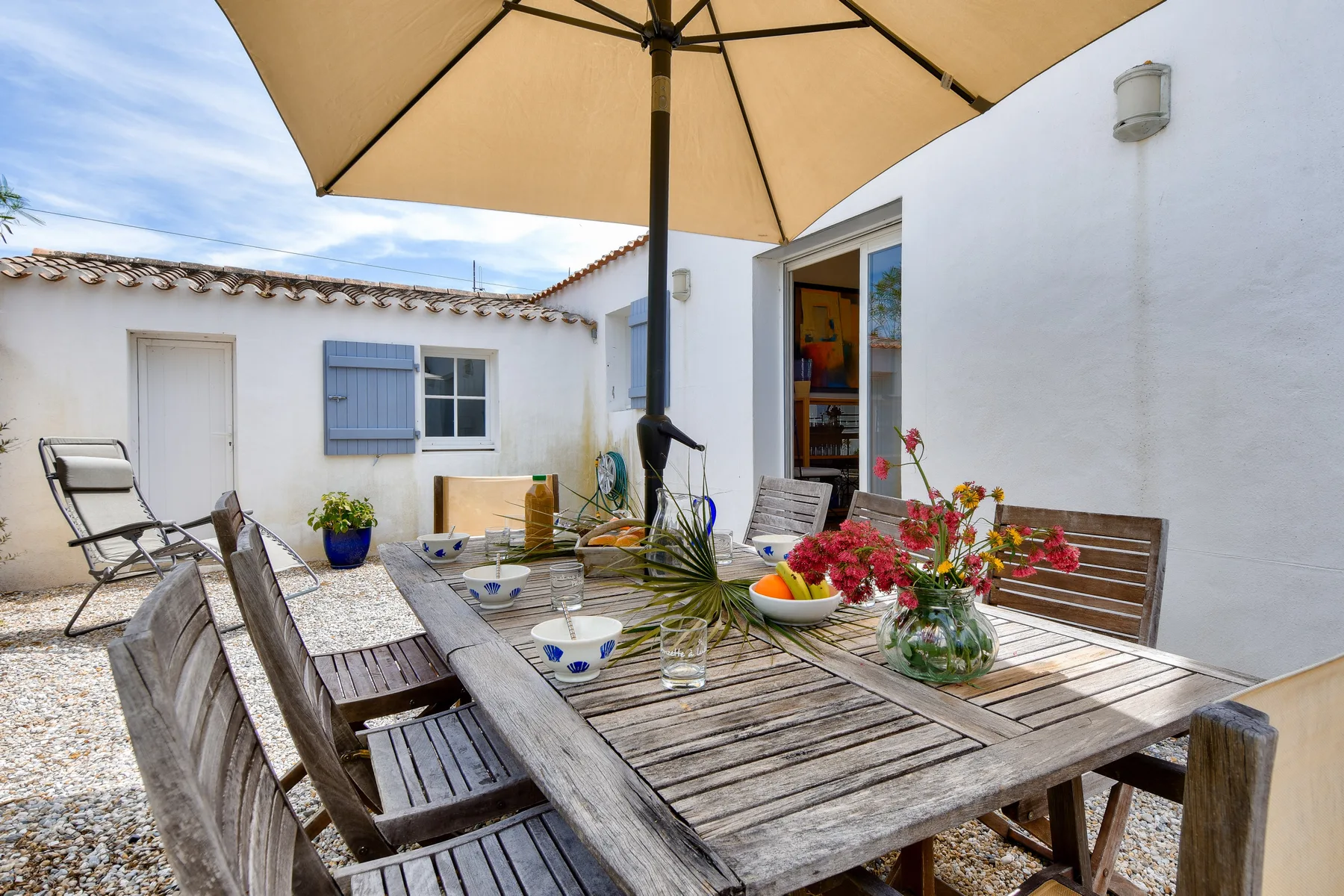 Outdoor dining area with a wooden table beneath a large umbrella.